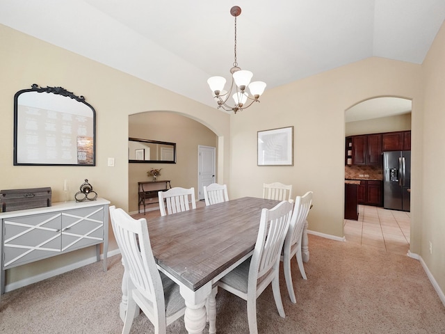 dining area with light colored carpet, arched walkways, vaulted ceiling, baseboards, and a chandelier