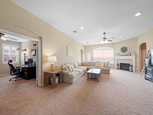 carpeted living room with plenty of natural light, arched walkways, and ceiling fan