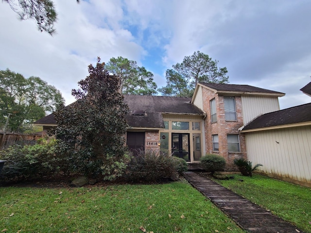 view of front facade with brick siding, a front lawn, and fence