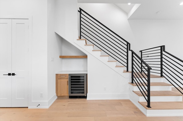 stairway with wood finished floors, baseboards, a bar, wine cooler, and recessed lighting