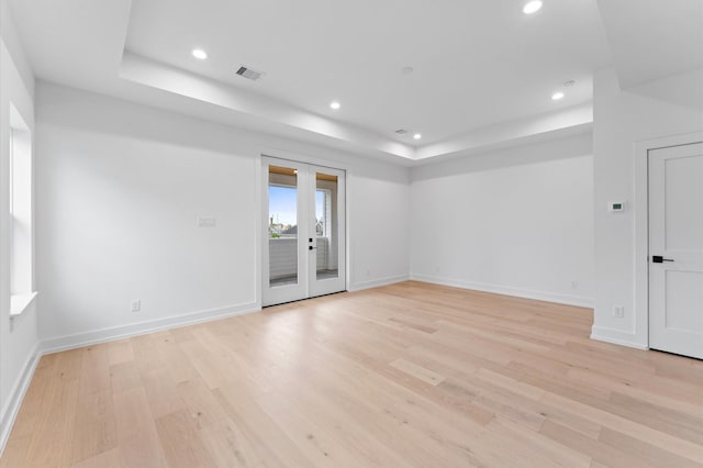 unfurnished room with recessed lighting, light wood-style flooring, a raised ceiling, and visible vents