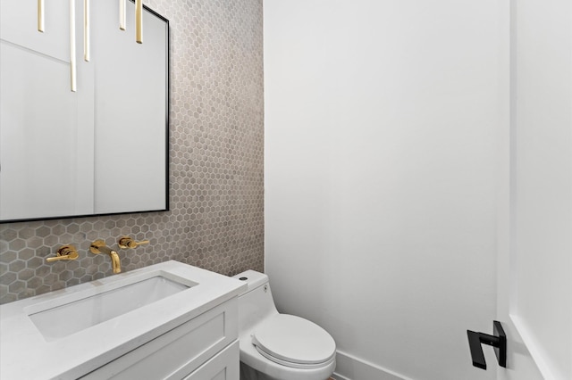 half bath with backsplash, tile walls, vanity, baseboards, and toilet