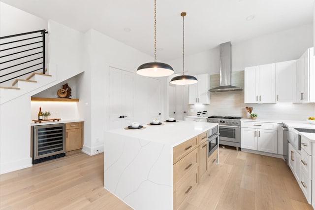 819 Dorothy St Unit A, Houston, TX 77008 - kitchen with wall chimney range hood, stainless steel appliances, wine cooler, a center island, and light wood-style floors