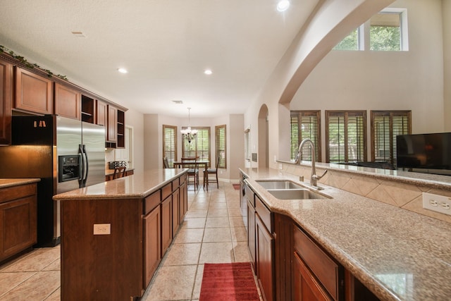 kitchen featuring stainless steel fridge, a sink, arched walkways, and a healthy amount of sunlight