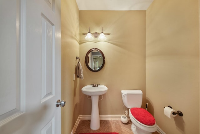 half bath with tile patterned floors, baseboards, and toilet