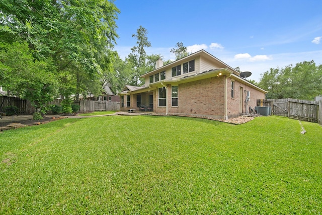 back of house with a fenced backyard, a chimney, a lawn, and brick siding