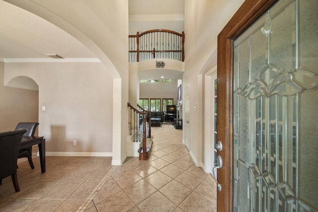 entryway with visible vents, crown molding, arched walkways, light tile patterned floors, and baseboards