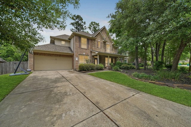 traditional home featuring a front lawn, fence, brick siding, an attached garage, and driveway