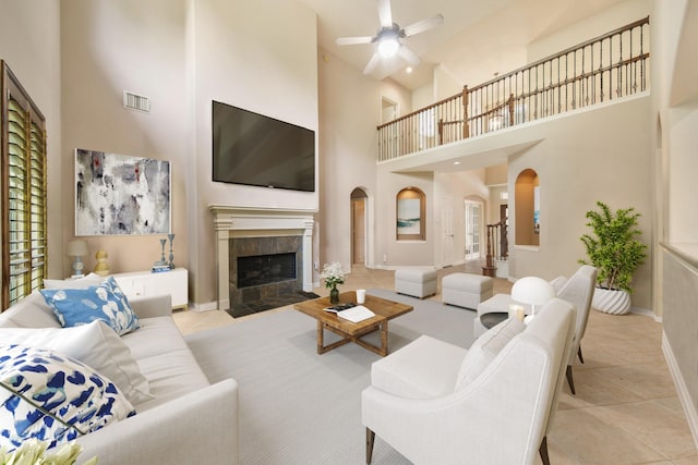 living area with visible vents, a ceiling fan, a towering ceiling, tile patterned floors, and arched walkways