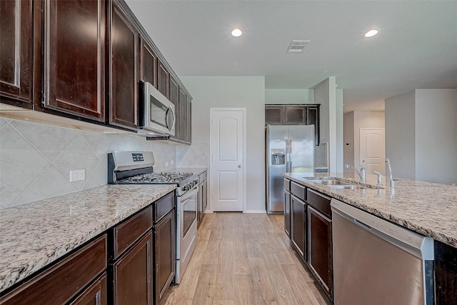 15314 Stulan Burn Dr, Humble, TX 77346 - kitchen featuring visible vents, appliances with stainless steel finishes, dark brown cabinets, a sink, and light wood-style floors