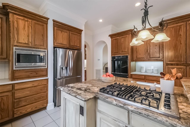 3210 Oakmont Dr, Sugar Land, TX 77479 - kitchen featuring arched walkways, decorative backsplash, stainless steel appliances, and brown cabinets