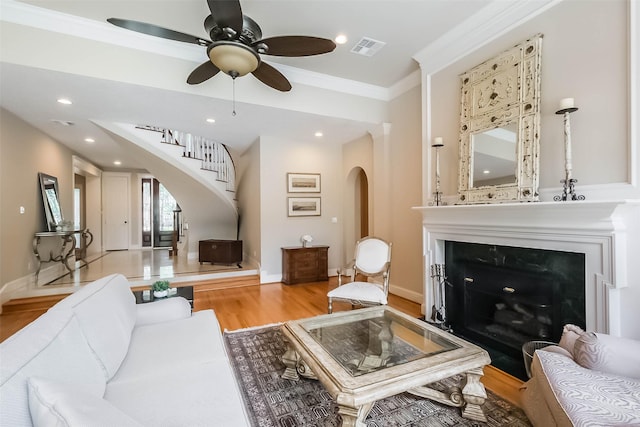 3210 Oakmont Dr, Sugar Land, TX 77479 - living room featuring ceiling fan, visible vents, arched walkways, light wood finished floors, and stairs