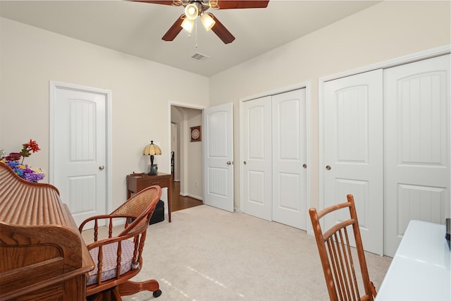 home office with light carpet, a ceiling fan, and visible vents