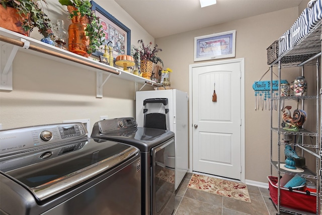 laundry room featuring laundry area, baseboards, dark tile patterned flooring, and washing machine and clothes dryer