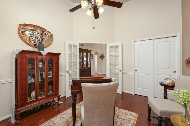 interior space with crown molding, a ceiling fan, dark wood finished floors, and a towering ceiling