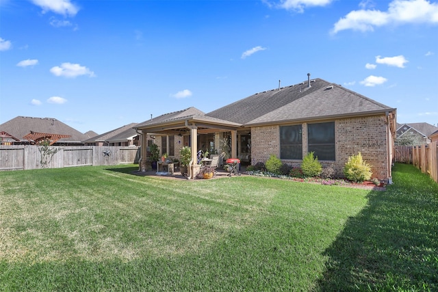 rear view of house featuring a patio, a fenced backyard, a lawn, and brick siding