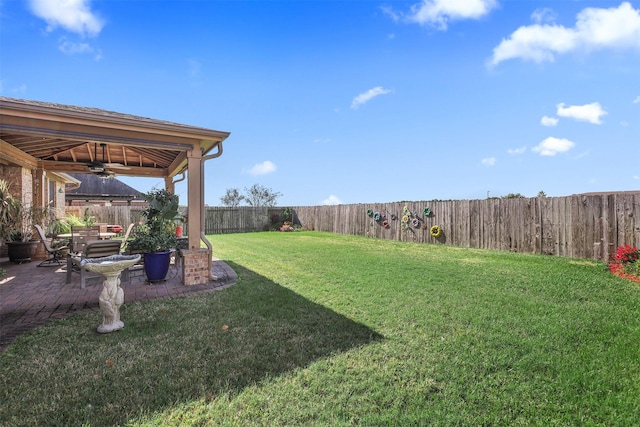 view of yard with a ceiling fan, a fenced backyard, and a patio area