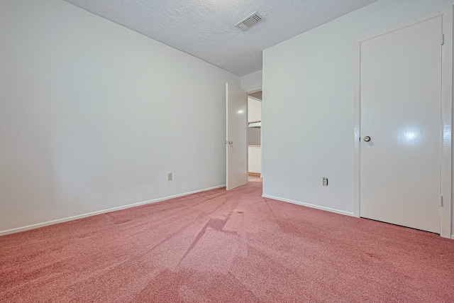 unfurnished bedroom featuring a textured ceiling, light colored carpet, baseboards, and visible vents