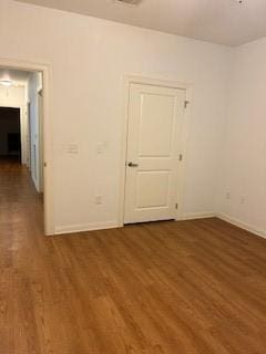 spare room featuring baseboards and wood finished floors