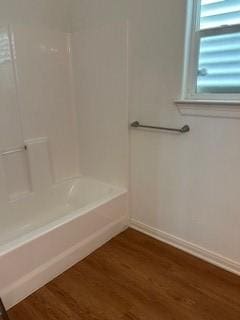 bathroom featuring baseboards, shower / washtub combination, and wood finished floors