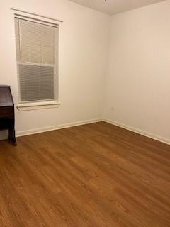 unfurnished room with baseboards and dark wood-style floors