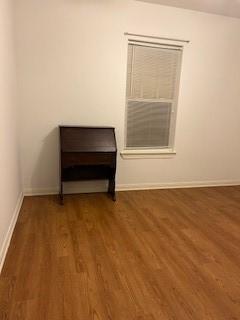 spare room with baseboards and wood finished floors