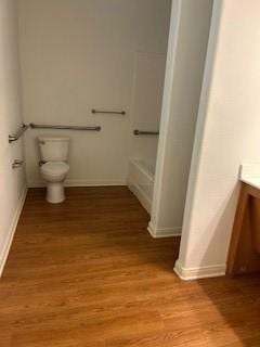 bathroom featuring toilet, baseboards, wood finished floors, and vanity