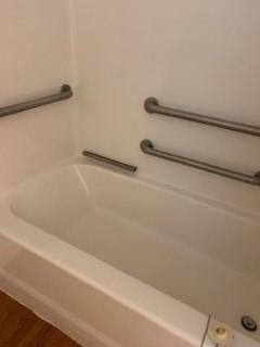 bathroom featuring wood finished floors and a tub to relax in