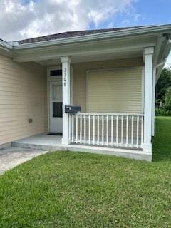 entrance to property featuring a porch and a lawn