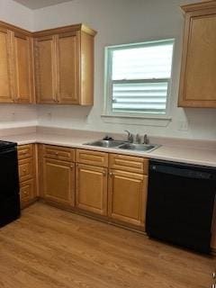 kitchen featuring dishwasher, light countertops, a sink, light wood finished floors, and range