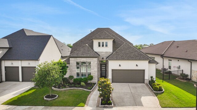 french country style house with driveway, a front lawn, stone siding, and a garage