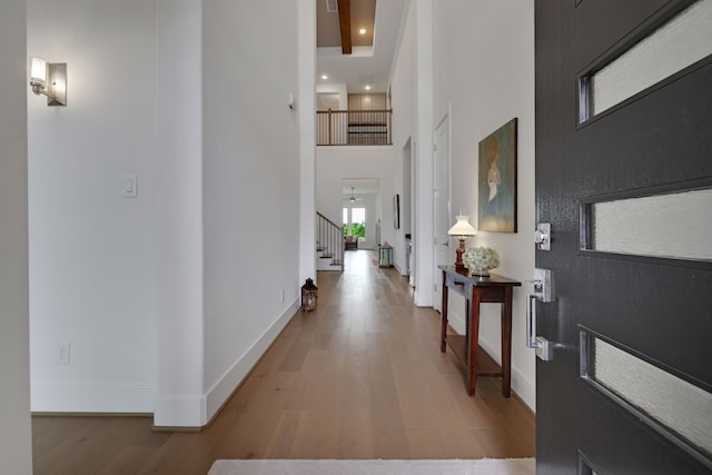 foyer entrance featuring a towering ceiling, wood finished floors, baseboards, stairway, and recessed lighting