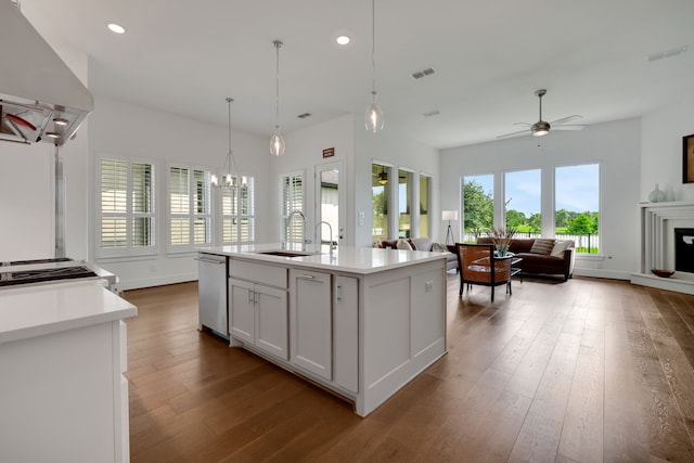 kitchen with stainless steel dishwasher, a sink, wall chimney exhaust hood, and light countertops