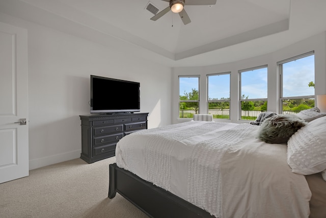 bedroom featuring a ceiling fan, light colored carpet, visible vents, baseboards, and a tray ceiling