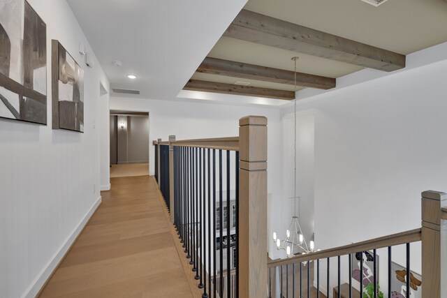 hall featuring visible vents, beam ceiling, an upstairs landing, an inviting chandelier, and light wood-style flooring