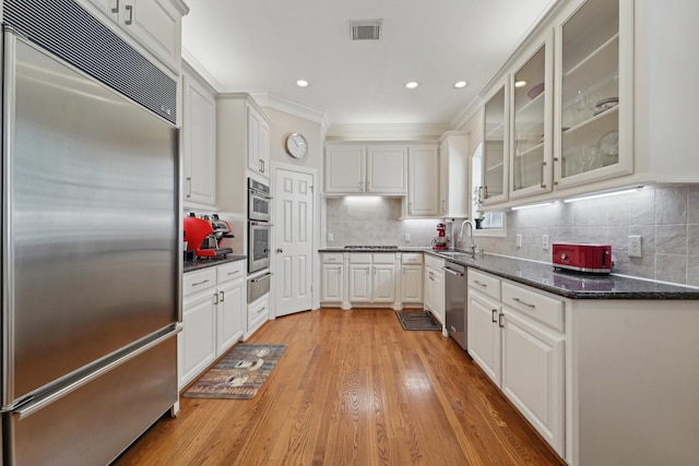 kitchen featuring visible vents, light wood-type flooring, a warming drawer, stainless steel appliances, and white cabinetry