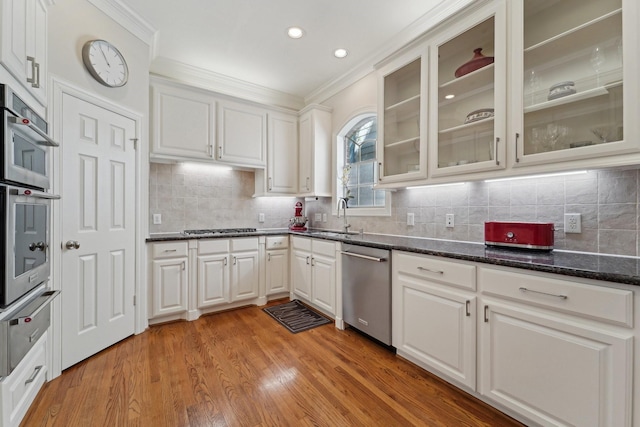 kitchen featuring crown molding, white cabinets, a sink, appliances with stainless steel finishes, and a warming drawer