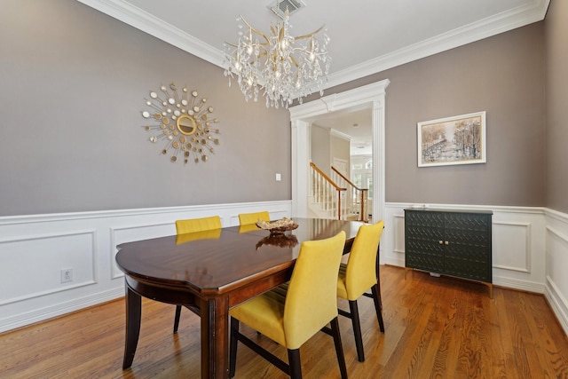 dining space with crown molding, a chandelier, visible vents, and a wainscoted wall