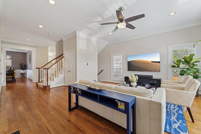 living room featuring plenty of natural light, ornamental molding, and stairway