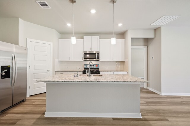 5030 Magnolia Springs Dr, Pearland, TX 77584 - kitchen featuring appliances with stainless steel finishes, tasteful backsplash, light wood-type flooring, white cabinetry, and recessed lighting
