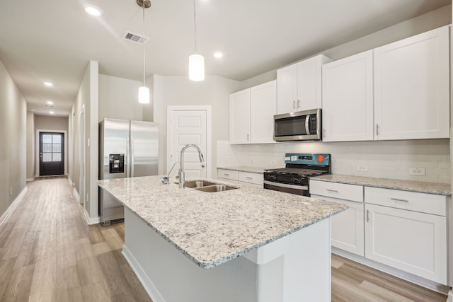 5030 Magnolia Springs Dr, Pearland, TX 77584 - kitchen with appliances with stainless steel finishes, a sink, light wood-style flooring, decorative backsplash, and a center island with sink