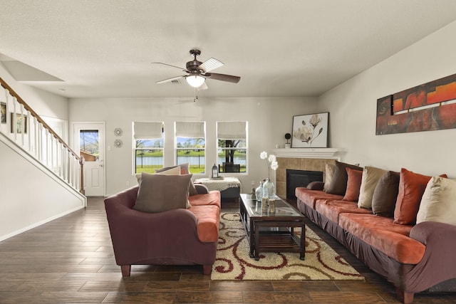 living area featuring a ceiling fan, wood finished floors, a tile fireplace, a water view, and stairway