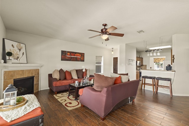 living room featuring a ceiling fan, baseboards, a tiled fireplace, and wood finished floors
