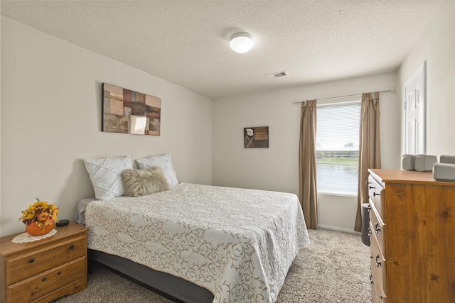 bedroom featuring visible vents, a textured ceiling, baseboards, and light colored carpet