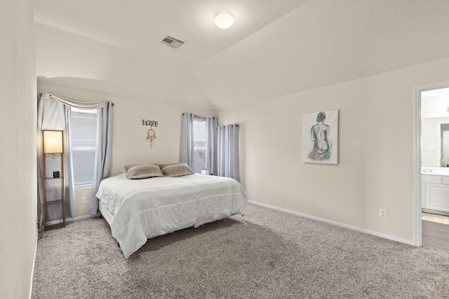 carpeted bedroom with visible vents, baseboards, connected bathroom, and lofted ceiling