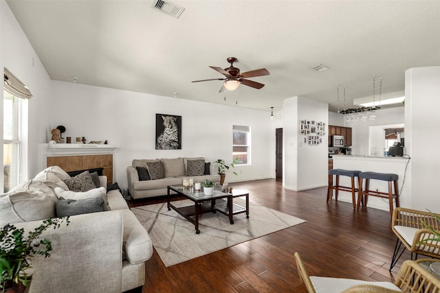 living area with ceiling fan, visible vents, and wood finished floors