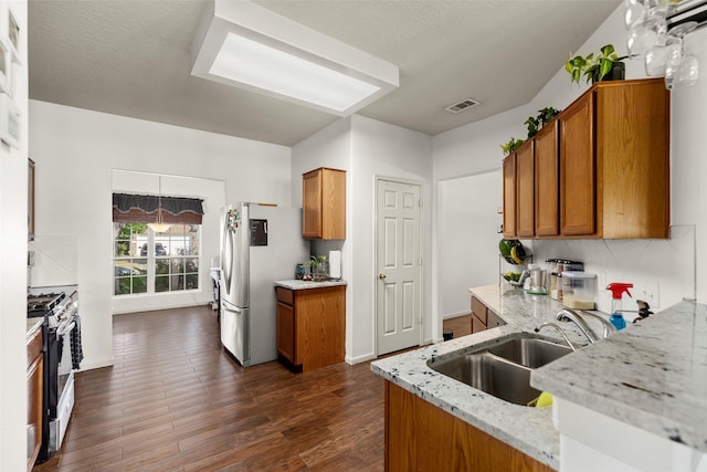 19527 Hardwood Ridge Trl, Cypress, TX 77429 - kitchen featuring appliances with stainless steel finishes, a sink, brown cabinets, and light stone counters