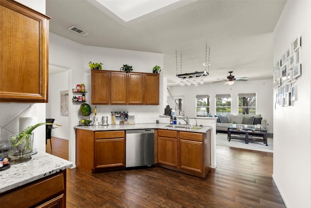 kitchen featuring visible vents, stainless steel dishwasher, brown cabinets, a sink, and a peninsula