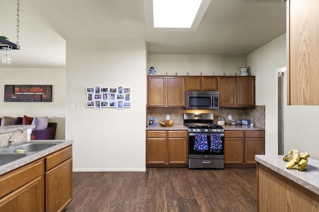 kitchen with dark wood-type flooring, brown cabinetry, appliances with stainless steel finishes, and backsplash