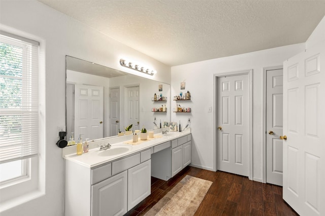 bathroom featuring a sink, double vanity, a textured ceiling, and wood finished floors